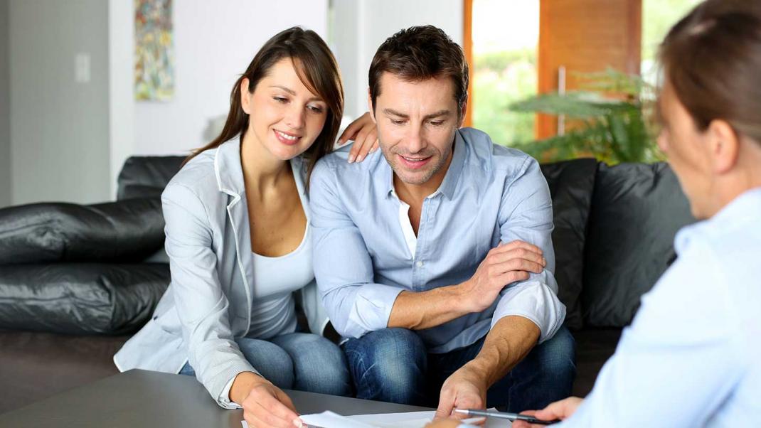 first time buyer couple talking to sales executive about buying new build home